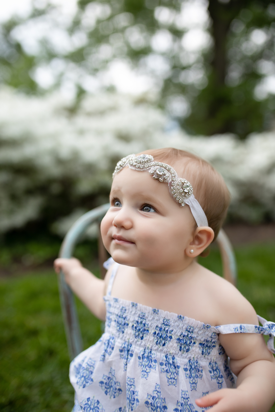 Baby sitting in chair with jeweled headband