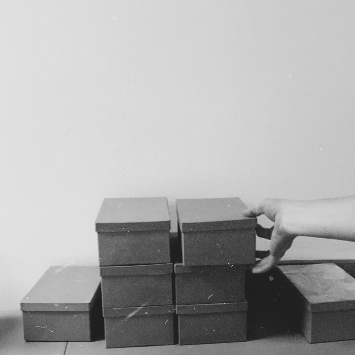 black and white image of stack of boxes with hand reaching for one