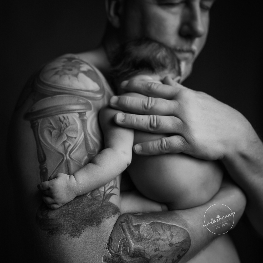 dad with tattoos holding newborn skin-to-skin