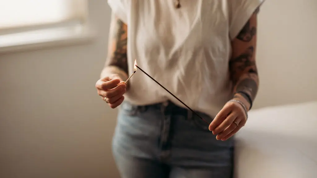 Woman lighting a stick of incense with a match
